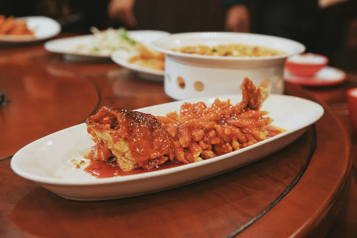 Battered meat with onion and bell pepper in a glossy sauce