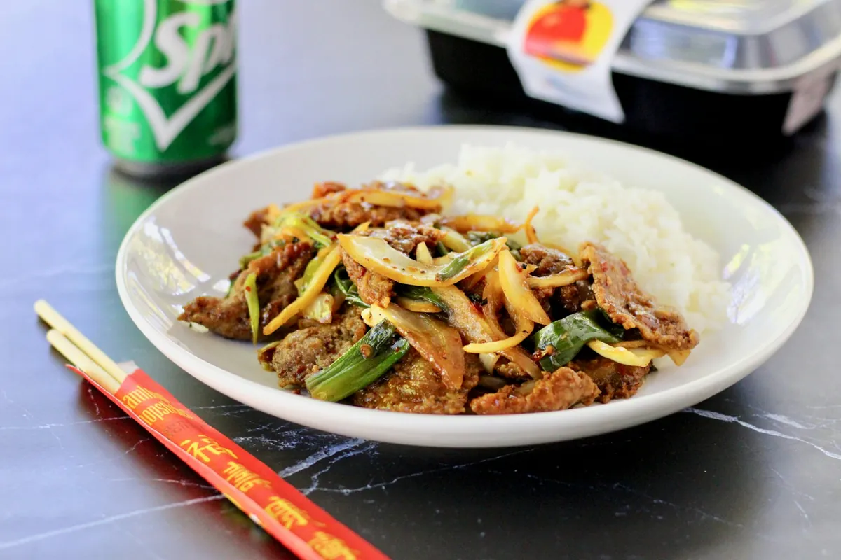 A plate of beef with peppers and onion