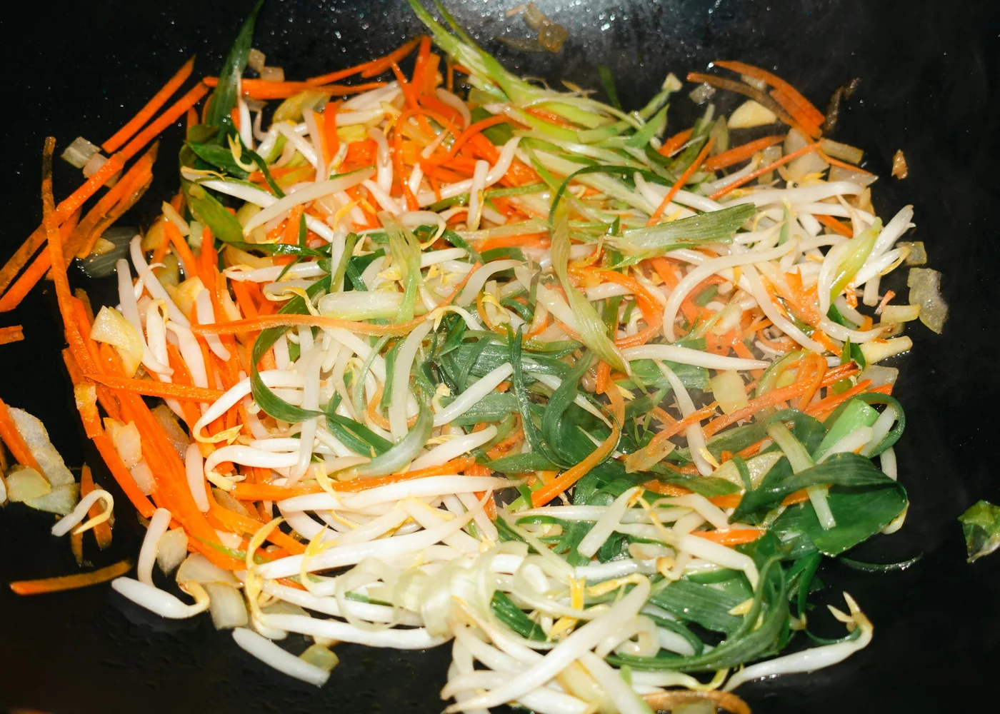 Shredded vegetables being cooked in a wok