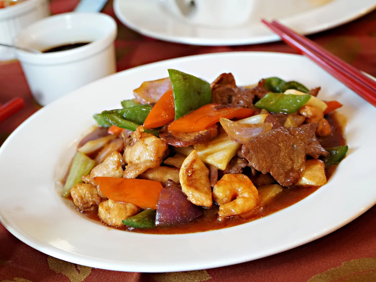 A stir-fried dish of shrimp, beef and chicken with vegetables