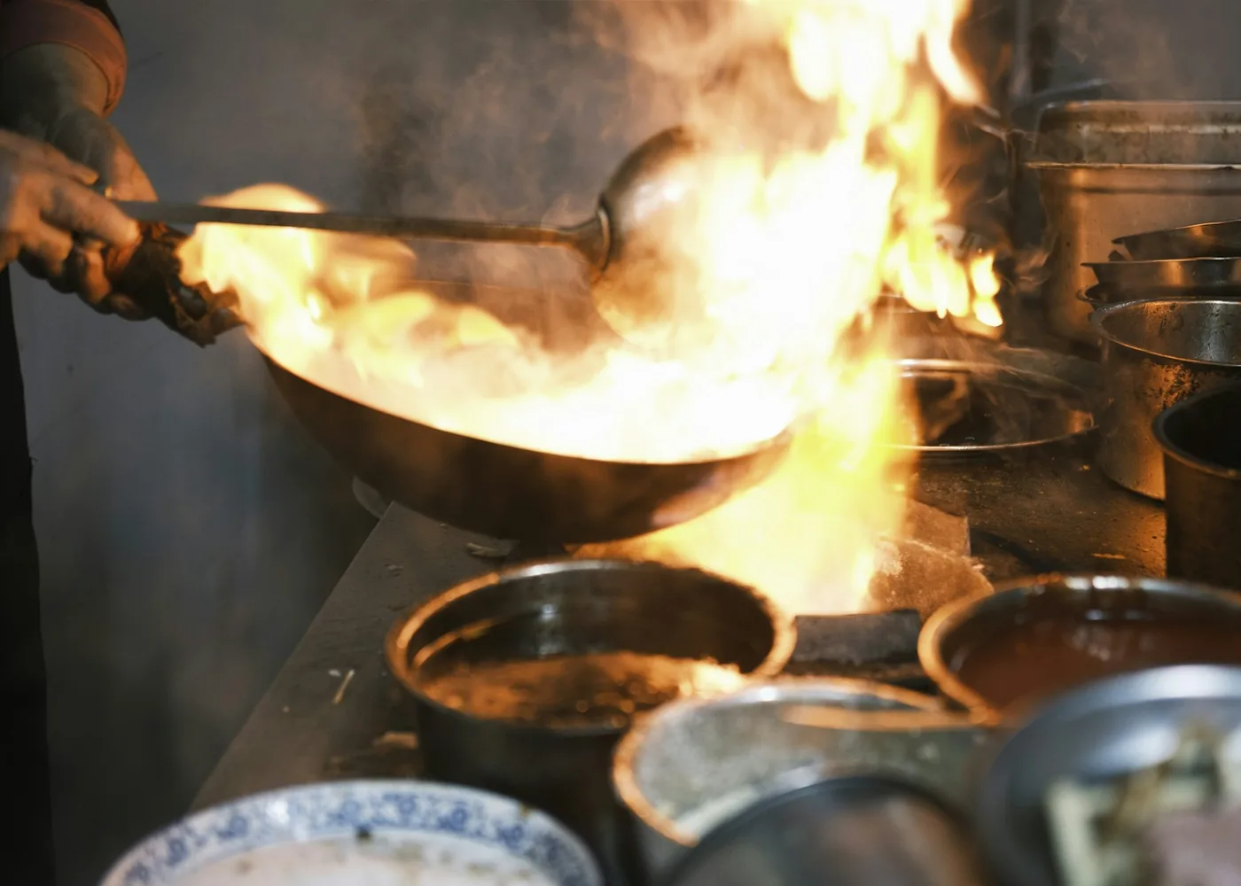 Cook tossing a stir-fry in a wok on a restaurant range