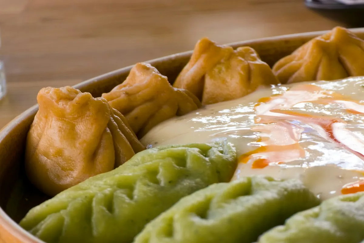 A small bowl of dipping sauce beside dumplings