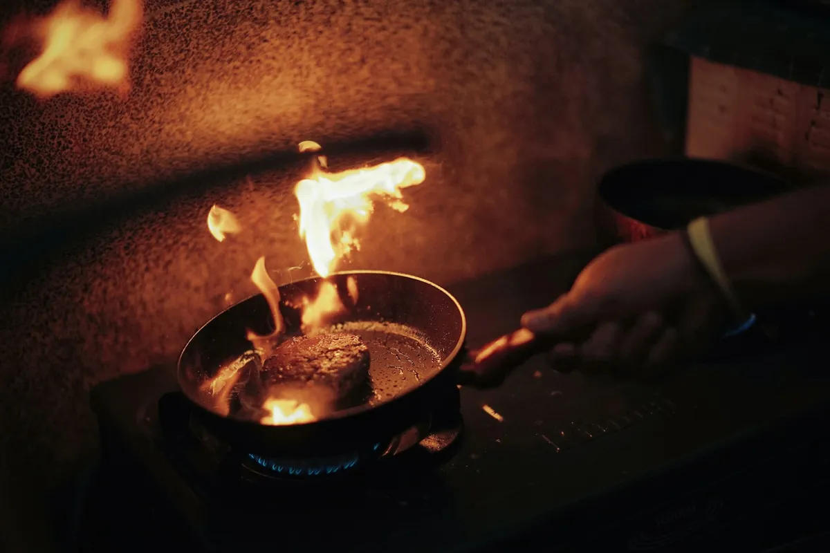 Flame briefly rising above a cooking pan