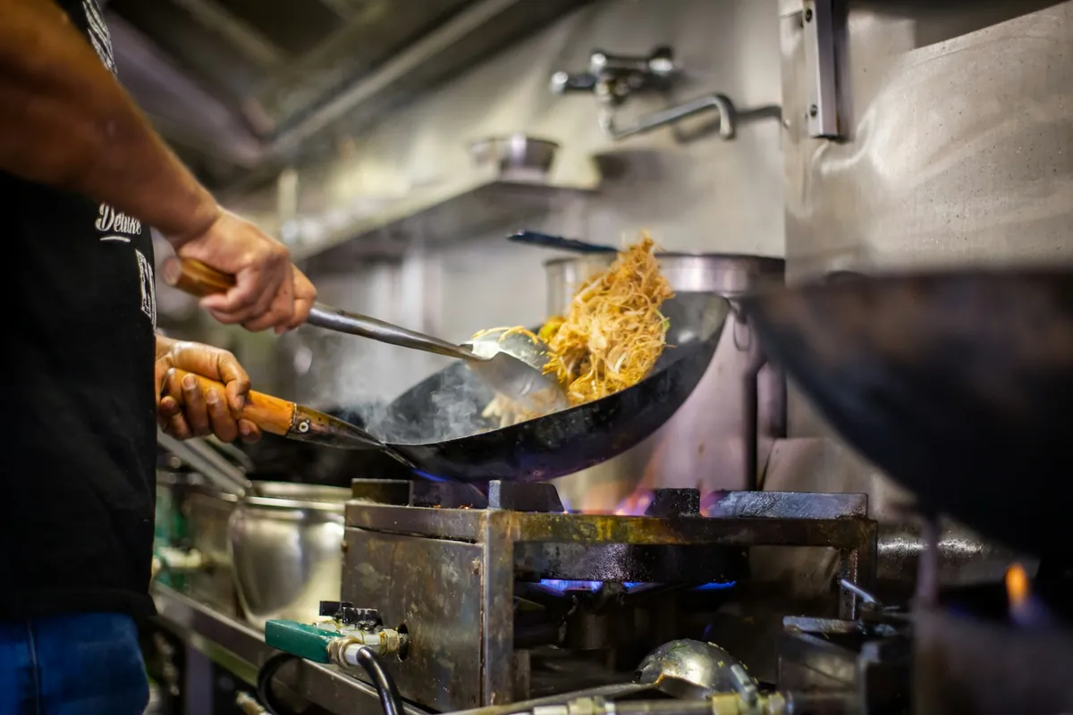 Food being tossed in a wok over high heat