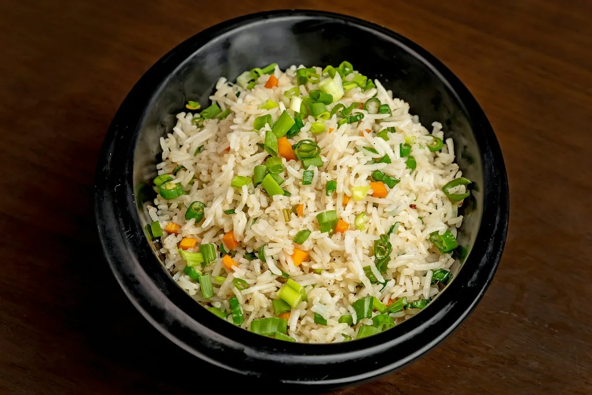 Fried rice served beside a sauced Chinese entree