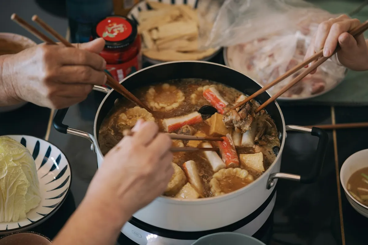 A group of people eating around a hot pot