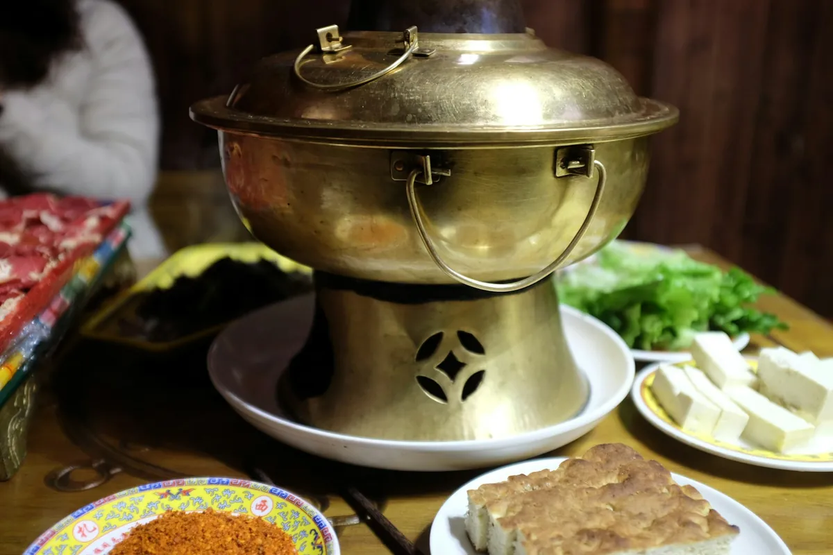 A full hot pot table with many plates around the pot