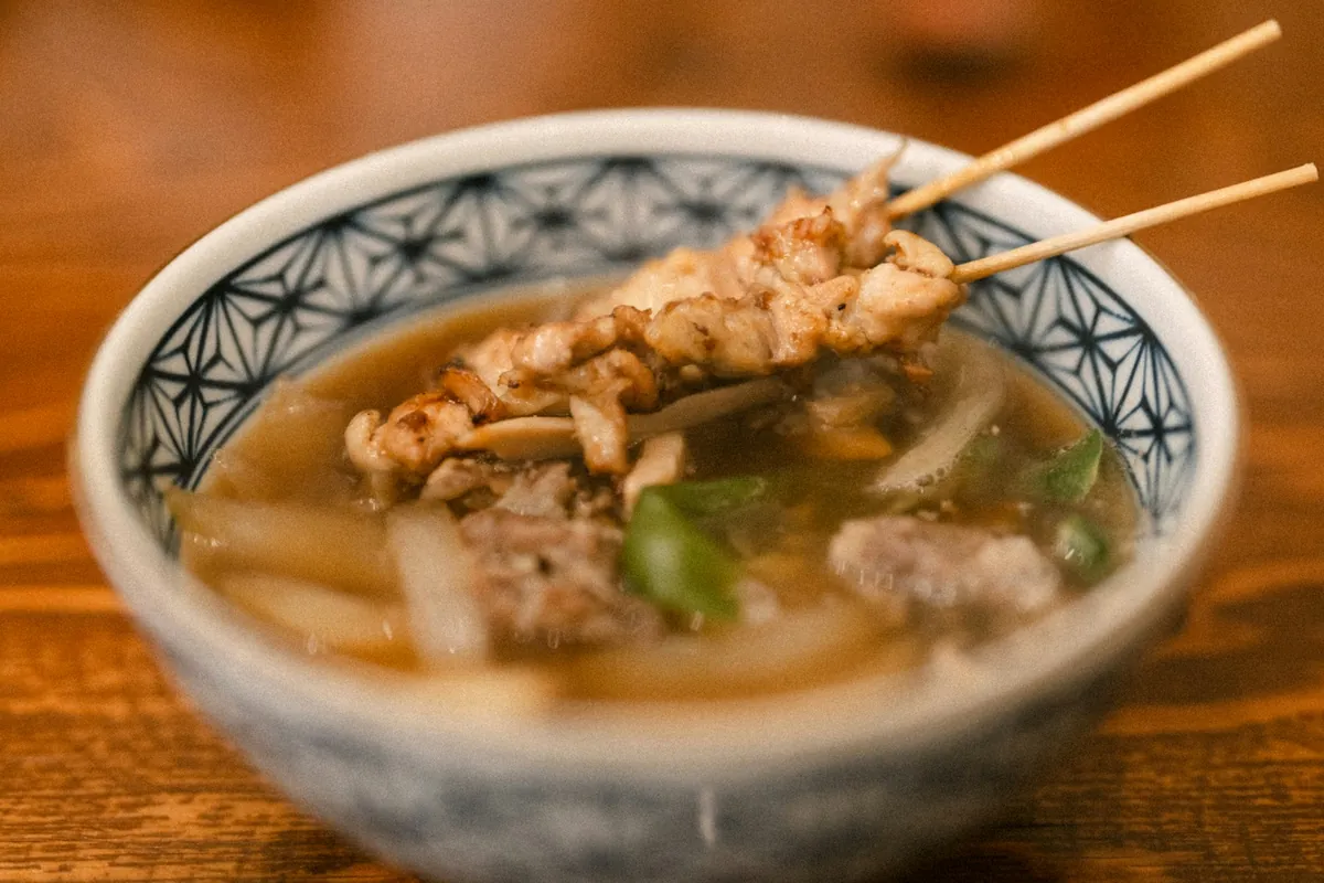 Food being lifted from a simmering broth with chopsticks