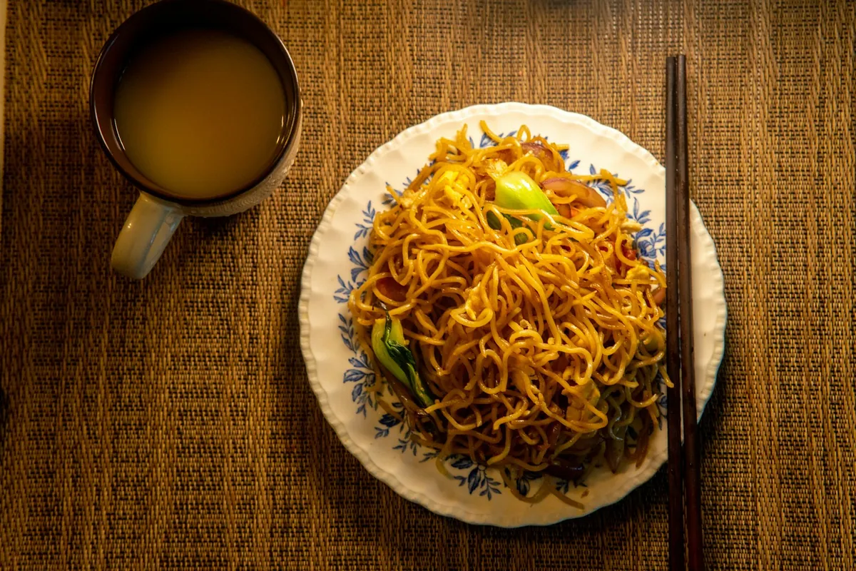 Noodles being tossed in a wok over high heat