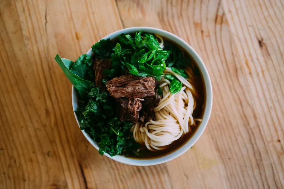 A stir-fried beef dish packed in a takeout container