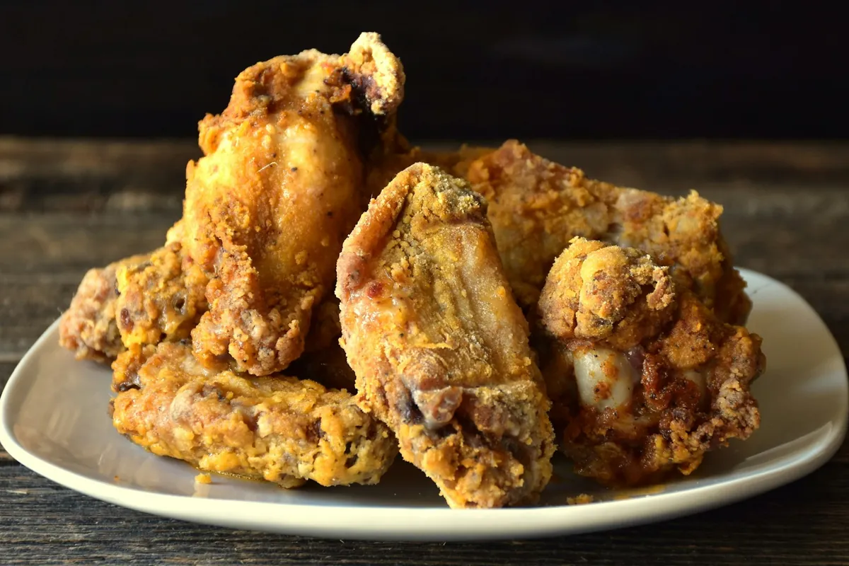 Chicken being coated in a wet batter